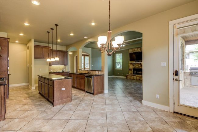 Kitchen featuring a sink, dishwasher, open floor plan, arched walkways, and an inviting chandelier | Image 12
