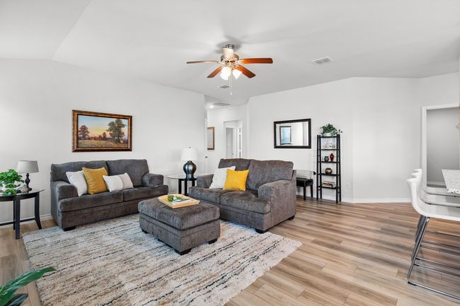 Living room with ceiling fan and light wood finished floors | Image 11