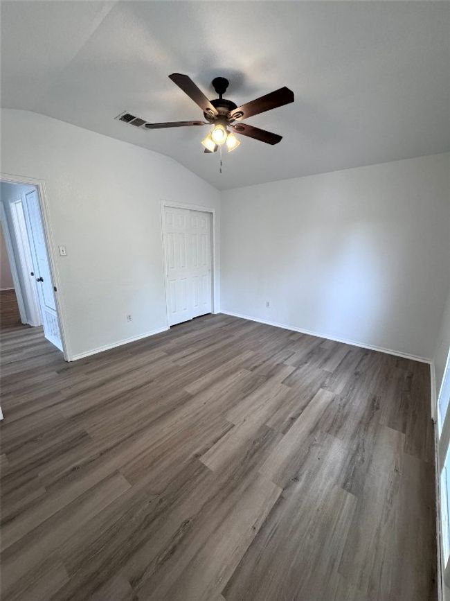 Empty room with vaulted ceiling, a ceiling fan, and dark wood finished floors | Image 27