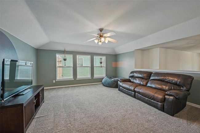 Living room with carpet flooring, a ceiling fan, baseboards, and lofted ceiling | Image 27
