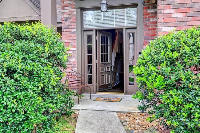 Welcome home to this inviting entryway, surrounded by lush greenery and charming brickwork. Step inside and feel at ease. | Image 4