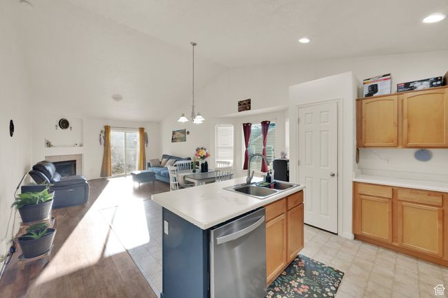 Kitchen with stainless steel dishwasher, vaulted ceiling, plenty of natural light, open floor plan, and a tile fireplace | Image 6