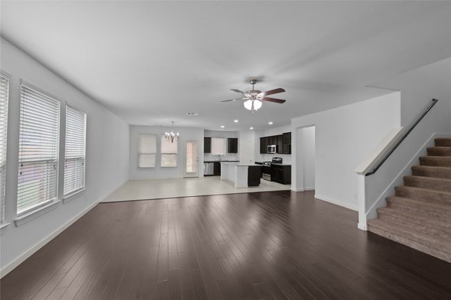 Unfurnished living room featuring a chandelier, a ceiling fan, stairway, recessed lighting, and wood finished floors | Image 13