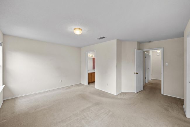 Unfurnished bedroom featuring light carpet, baseboards, and ensuite bath | Image 17