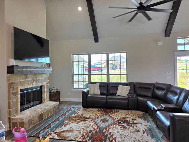 Living area with wood finished floors, ceiling fan, a fireplace, and recessed lighting | Image 7
