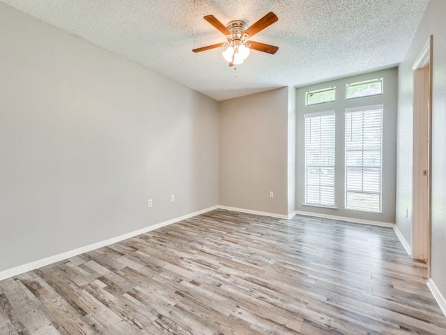 Empty room with a textured ceiling, ceiling fan, and wood finished floors | Image 9