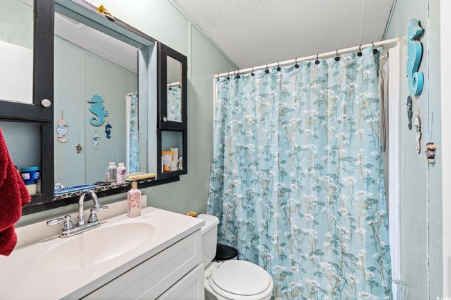 Bathroom featuring toilet, vanity, curtained shower, and a textured ceiling | Image 15