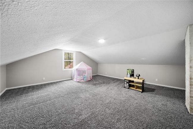 Bonus room with lofted ceiling, a textured ceiling, carpet flooring, and baseboards | Image 18