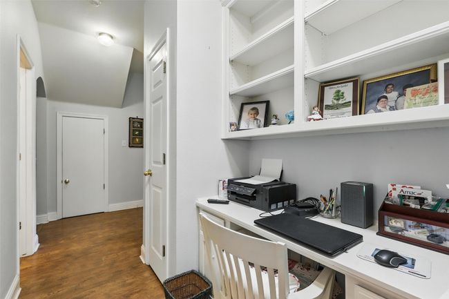 Office space with dark wood-type flooring, built in study area, and arched walkways | Image 25