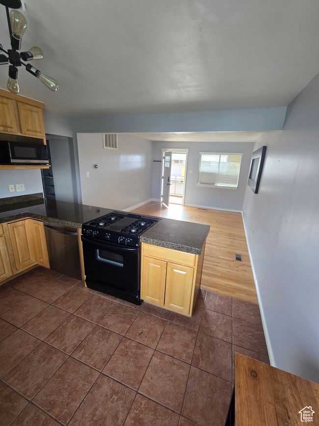Kitchen featuring black appliances, dark countertops, light brown cabinets, and dark tile patterned floors | Image 13