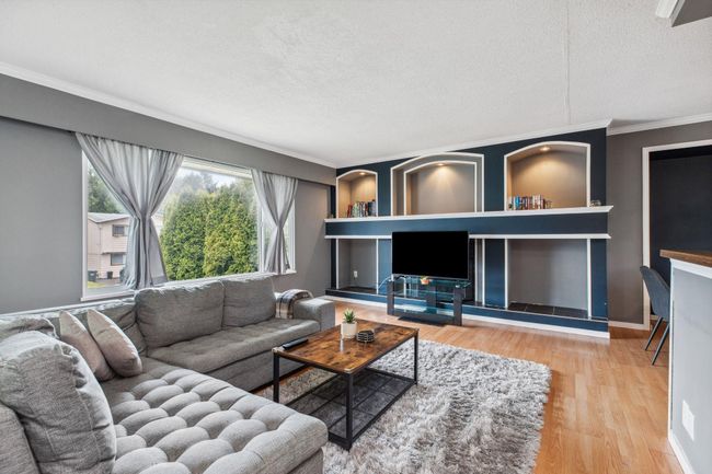 Living room with a textured ceiling, wood finished floors, baseboards, and ornamental molding | Image 4
