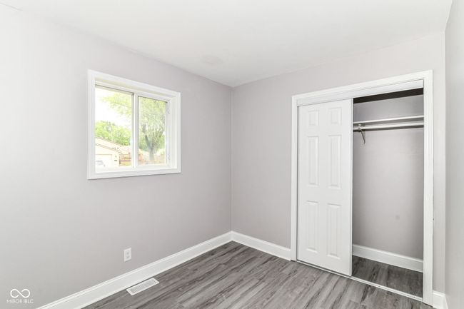 unfurnished bedroom featuring wood finished floors, baseboards, and a closet | Image 18