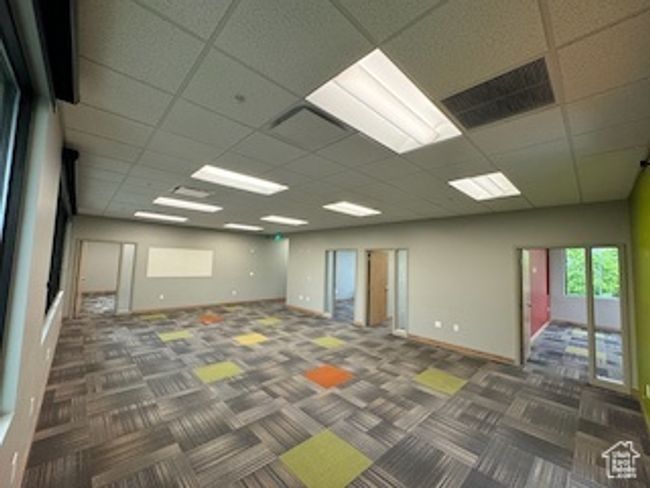 Carpeted empty room with a paneled ceiling and baseboards | Image 8