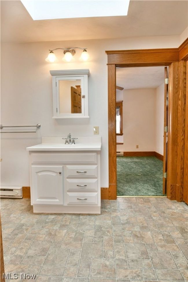 Bathroom with tile floors, large vanity, baseboard heating, and a skylight | Image 19