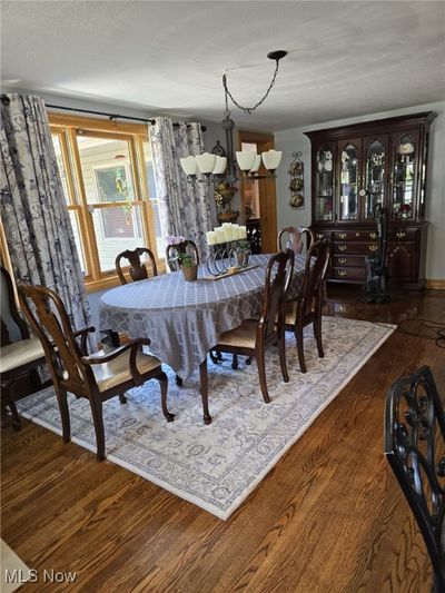 Dining space featuring dark hardwood / wood-style flooring, a textured ceiling, and a chandelier | Image 2