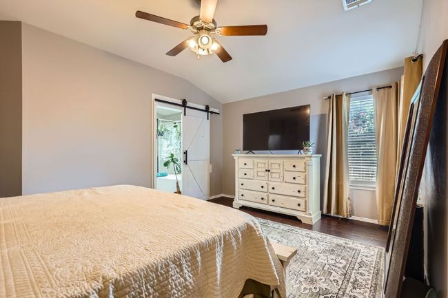 Bedroom with lofted ceiling, a barn door, dark wood-type flooring, and ceiling fan | Image 12