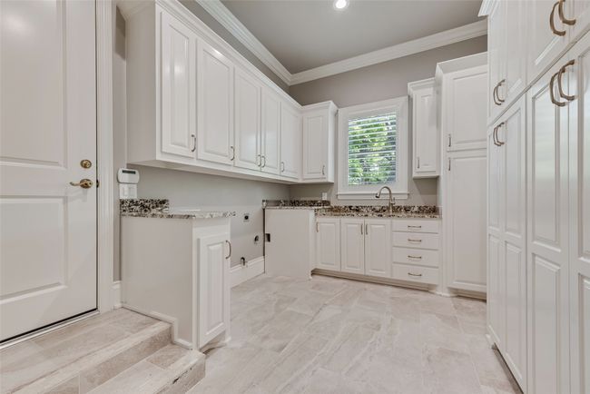 Laundry room featuring a sink, hookup for an electric dryer, cabinet space, washer hookup, and crown molding | Image 18