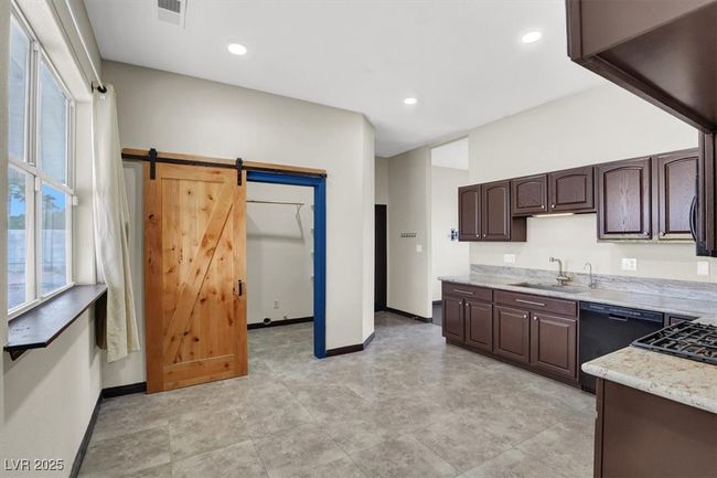Kitchen featuring a sink, a barn door, dark brown cabinets, baseboards, and dishwasher | Image 14