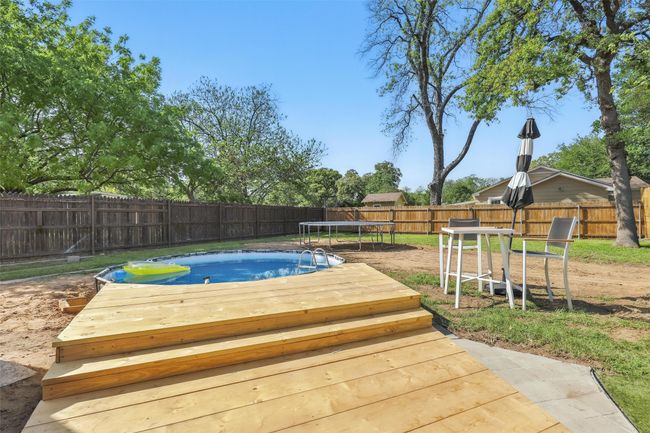 View of pool featuring a trampoline, a wooden deck, and a fenced backyard | Image 37