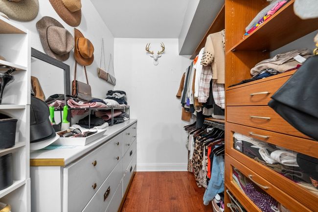 Spacious walk-in closet in primary bedroom featuring wood-style flooring, dresser drawers and shelves | Image 31