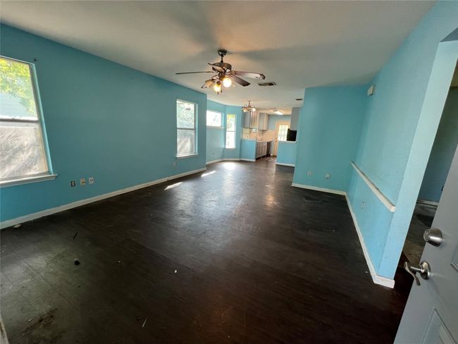 Unfurnished living room with a ceiling fan, baseboards, and wood finished floors | Image 11