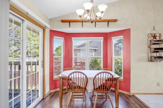 Dining area with a chandelier, lofted ceiling, wood finished floors, and baseboards | Image 9