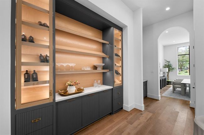 This sophisticated lounge features custom built-in cabinetry with illuminated shelving, creating a warm and inviting space perfect for displaying décor or entertaining in style. | Image 9