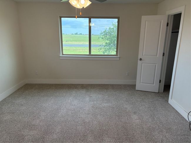 Empty room with carpet flooring, a ceiling fan, and baseboards | Image 7