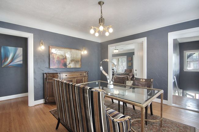 Dining room with a textured wall, a notable chandelier, baseboards, and wood finished floors | Image 18