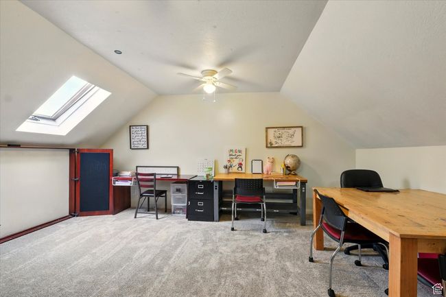 Carpeted office with vaulted ceiling, a skylight, and ceiling fan | Image 30