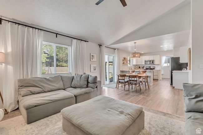 Living area featuring plenty of natural light, a ceiling fan, light wood-style flooring, and lofted ceiling | Image 5