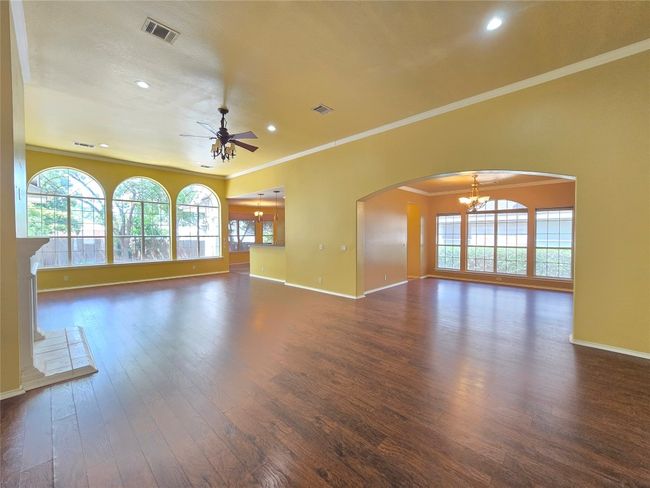 Unfurnished living room featuring a chandelier, dark wood finished floors, a ceiling fan, arched walkways, and recessed lighting | Image 10