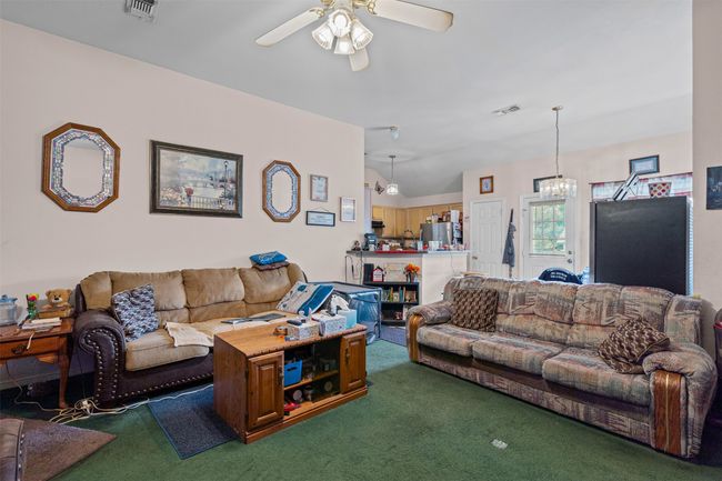 Living room featuring carpet floors, a ceiling fan, lofted ceiling, and a chandelier | Image 8