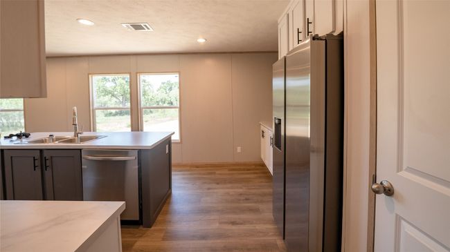 Kitchen with appliances with stainless steel finishes, light wood-type flooring, light countertops, recessed lighting, and white cabinets | Image 25