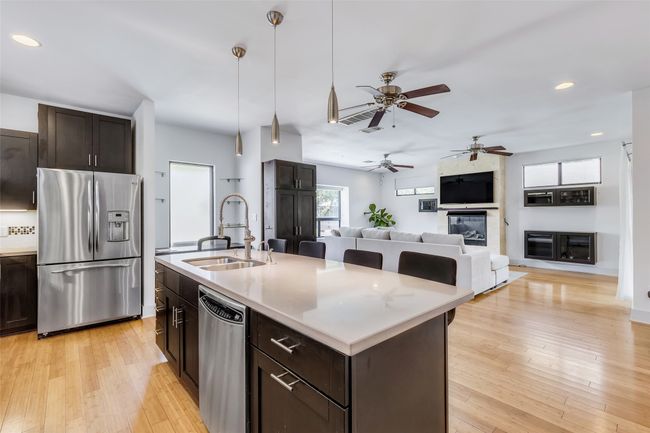 Kitchen featuring light hardwood / wood-style flooring, stainless steel appliances, sink, hanging light fixtures, and a center island with sink | Image 5