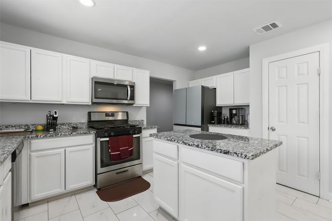 Kitchen featuring appliances with stainless steel finishes, white cabinetry, dark stone countertops, and recessed lighting | Image 9