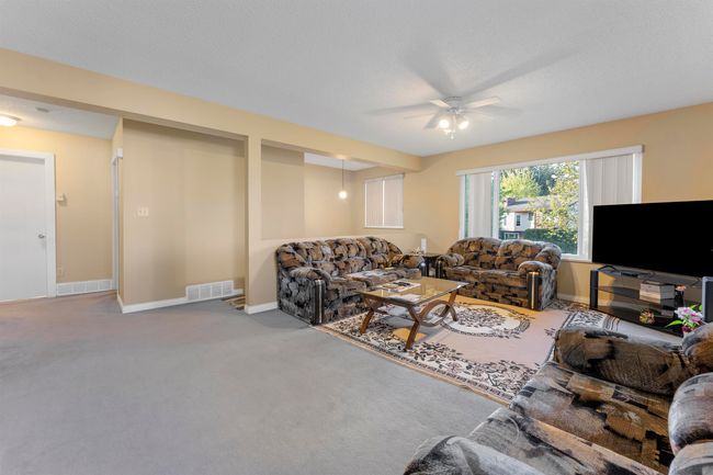 Living area with carpet flooring, baseboards, a ceiling fan, and visible vents | Image 8