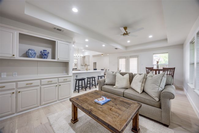 Living room featuring a tray ceiling, light wood finished floors, a ceiling fan, recessed lighting, and a chandelier | Image 14