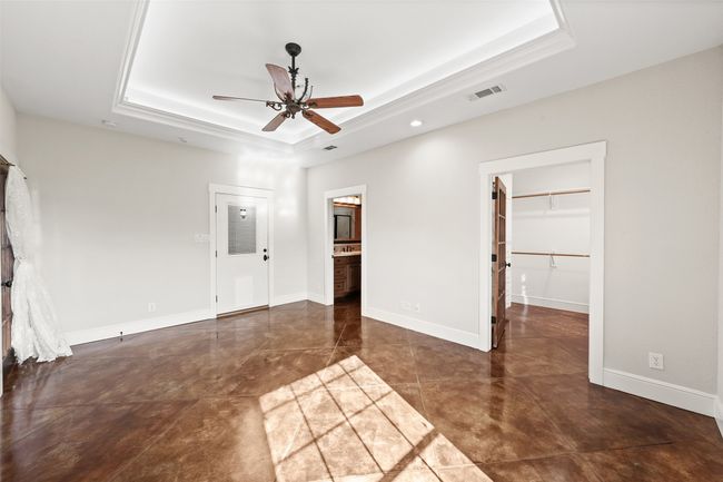 Unfurnished bedroom with a tray ceiling, a walk in closet, connected bathroom, baseboards, and recessed lighting | Image 18