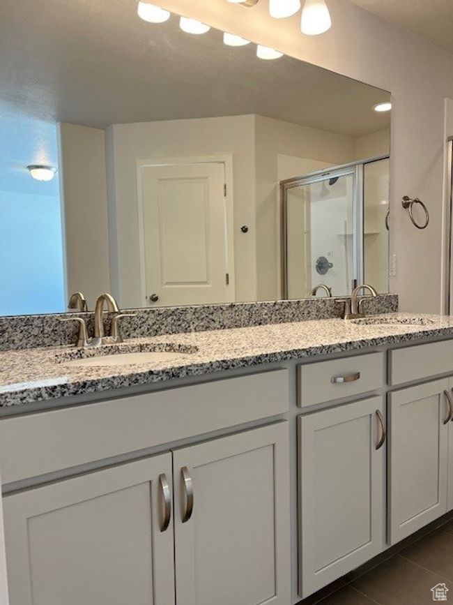 Bathroom featuring a stall shower, tile patterned floors, double vanity, and a sink | Image 7