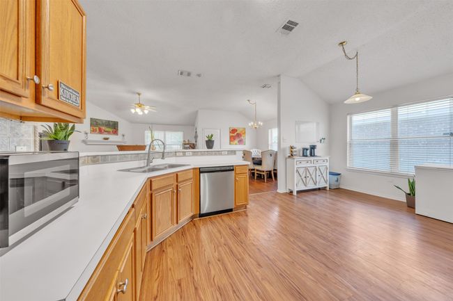 Kitchen featuring vaulted ceiling, stainless steel appliances, light wood-style floors, a peninsula, and light countertops | Image 8
