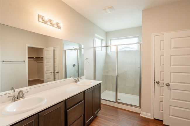 Full bath featuring wood finished floors, a spacious closet, a sink, and a stall shower | Image 25