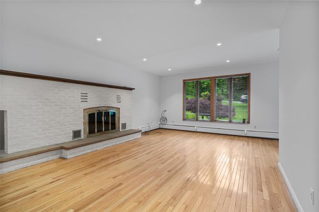 Unfurnished living room with wood-type flooring, a fireplace, baseboard heating, and recessed lighting | Image 6
