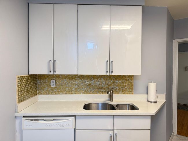 Kitchen featuring white dishwasher, light countertops, and white cabinetry | Image 4