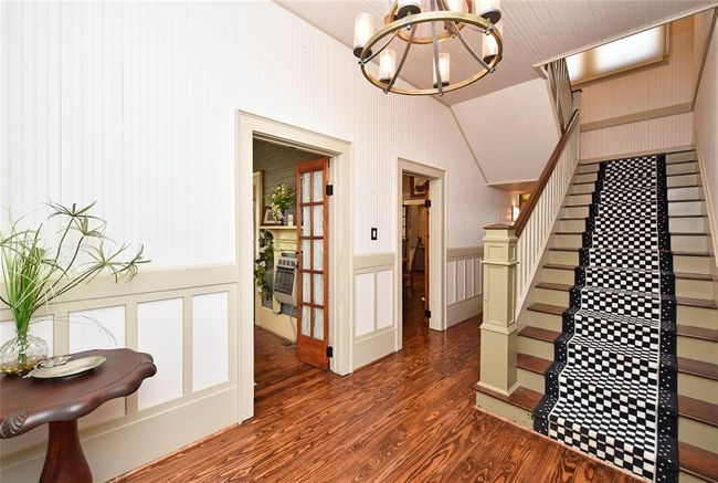 The foyer in the Main home welcomes guests with period specific lighting, bead-board walls, original wood flooring and pure charm. | Image 8