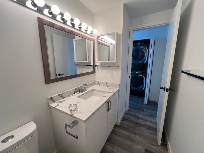 Bathroom featuring stacked washing machine and dryer, vanity, and wood finished floors | Image 30
