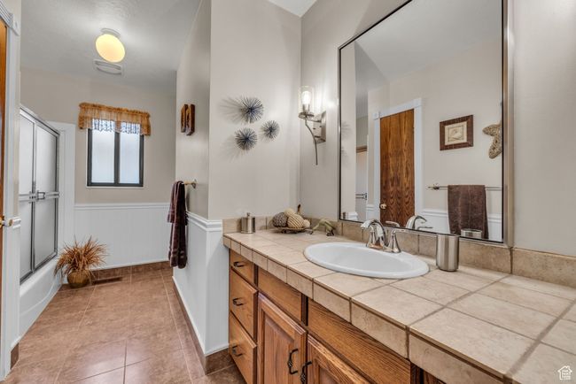 Full bathroom with vanity, a wainscoted wall, tile patterned flooring, and enclosed tub / shower combo | Image 12