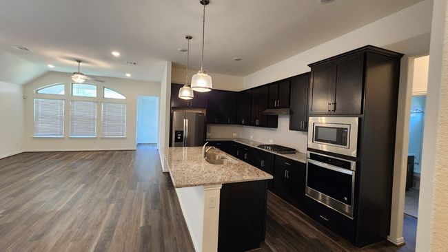 Kitchen featuring appliances with stainless steel finishes, a sink, ceiling fan, light stone counters, and under cabinet range hood | Image 5