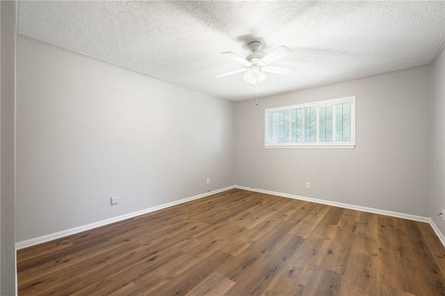 Empty room with baseboards, ceiling fan, a textured ceiling, and wood finished floors | Image 11