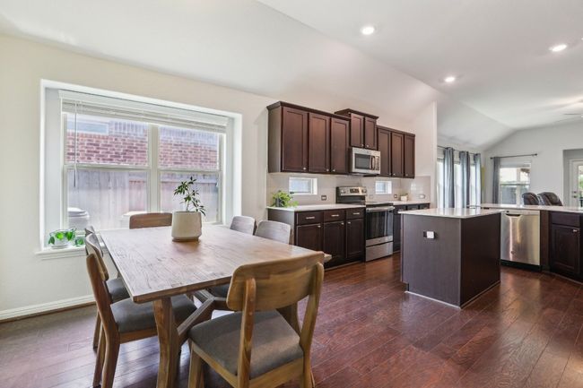 Kitchen with a center island, dark wood finished floors, dark brown cabinets, light countertops, and appliances with stainless steel finishes | Image 10